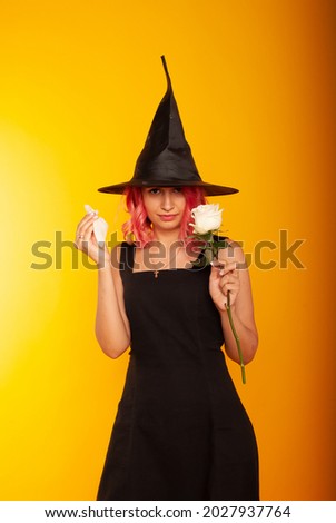 a woman witch with a rose in her hands smashes it for halloween while pronouncing a spell. Feast of evil spirits. Witch, place for text