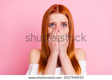 Portrait of attractive desperate worried red-haired girl closing mouth oops hide fear isolated over pink pastel color background