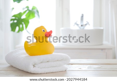 Towel and bath duck on table on blurred bathroom background