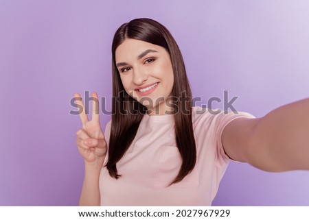Portrait of friendly optimistic dream lady hold camera make selfie show v-sign on purple background