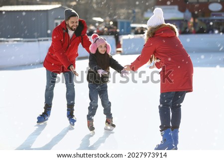 Happy family spending time together at outdoor ice skating rink Royalty-Free Stock Photo #2027973914
