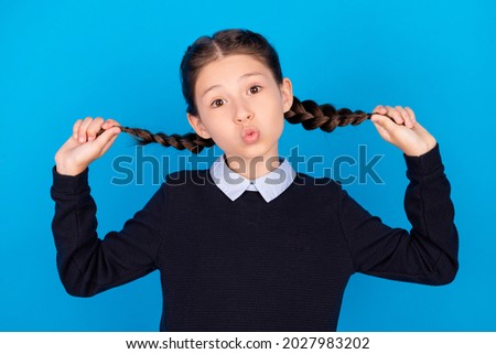 Photo of cheerful funny funky small girl hold hands braids good mood playful air kiss isolated on blue color background