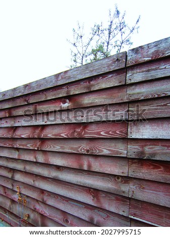 A high massive wooden fence with a clearly defined bright pattern of a wooden structure.
