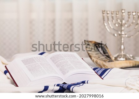 Open Torah book, Tallit and Shofar on table indoors. Rosh Hashanah holiday attributes Royalty-Free Stock Photo #2027998016