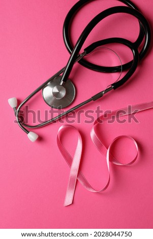 Breast cancer awareness ribbon and stethoscope on pink background