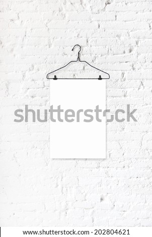 Hanger with white paper on a white brick wall