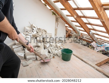 Construction worker with a shovel after demolishing  a brick wall in a private home. Royalty-Free Stock Photo #2028048212