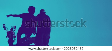 Video production behind the scenes. Making of TV commercial movie that film crew team lightman and cameraman working together with film director in studio. film production concept. Silhouette style. Royalty-Free Stock Photo #2028052487