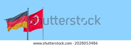 Banner with national black red yellow flag of Germany and red Turkish flag with white crescent moon and star at blue sky background with copy space. Concept of nationality, citizenship and patriotism