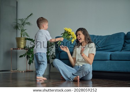 Happy mother day. child son congratulates mother on holiday and gives flowers. congratulating her on mother's day during holiday celebration at home