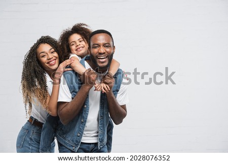 happy african american family looking at camera while hugging on grey Royalty-Free Stock Photo #2028076352