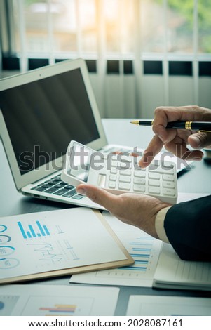 Businessman working with graph papers and laptop calculator to calculate company financial results. On a wooden table in offices and businesses, tax, accounting, statistics and vertical analytical res