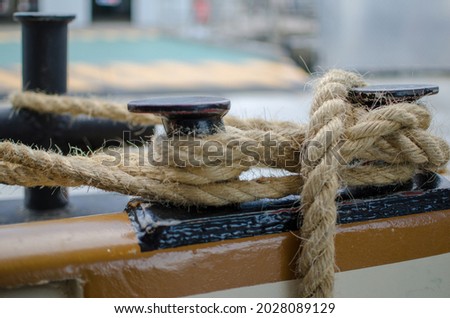 moored boat: rope with picture of the detail of the boat with a mooring line with a cleat knot to tie the ship to the docking port.