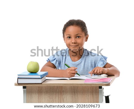 Little African-American pupil sitting at school desk against white background Royalty-Free Stock Photo #2028109673