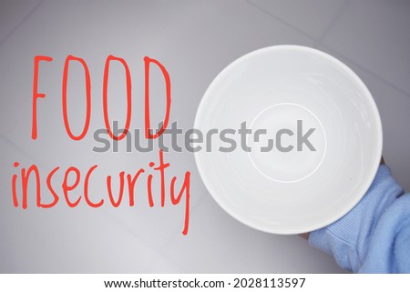 A concept of Covid-19 effect. A hand holding a plate with word FOOD INSECURITY. World problem. Royalty-Free Stock Photo #2028113597