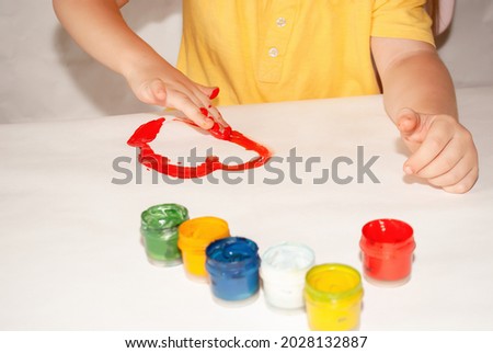 the girl draws a heart in red paint with bright colors on a sheet. place for text. school advertisement