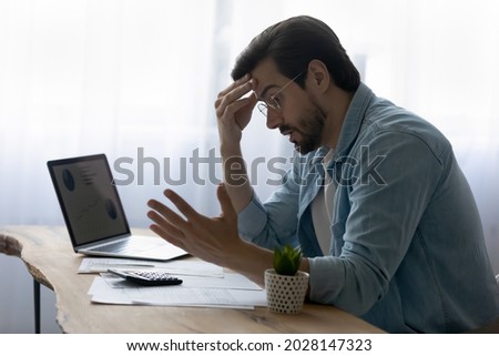 Stressed anxious young man feeling frustrated of made mistakes in financial payments, feeling lack of money calculating domestic expenses, paying bills or taxes online, bank debt bankruptcy concept. Royalty-Free Stock Photo #2028147323