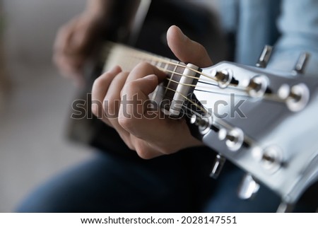 Close up young man playing string instrument, learning chords practicing music, enjoying rehearsal, improving creative skills. Professional male musician demonstrating excellent musical technique. Royalty-Free Stock Photo #2028147551