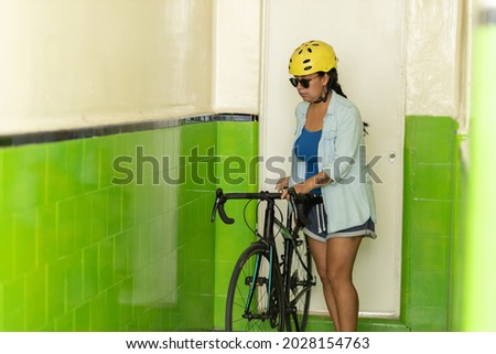 woman carrying her bicycle leaving her small apartment, urban cyclist concept