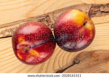 Two juicy ripe plums on a wooden table, close-up, top view.