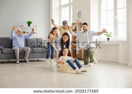 Reunion of generations. Happy big family with children have fun together at home playing. Mom, dad, little daughters and grandparents play with a plastic container in the living room Royalty-Free Stock Photo #2028177689
