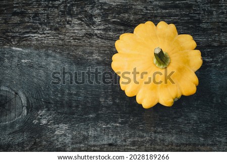 One pattypan vegetable on old wooden board, top view