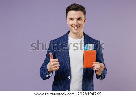 Traveler tourist fun young successful employee business man corporate lawyer 20s wear formal blue suit white t-shirt hold passport boarding tickets isolated on pastel purple background studio portrait