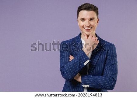 Smiling fun young successful employee business man corporate lawyer 20s wear formal blue suit white t-shirt work in office put hand prop up on chin isolated on pastel purple background studio portrait