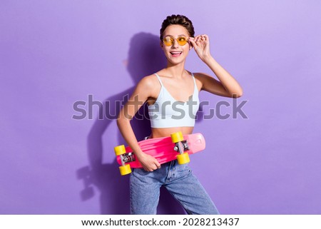 Photo portrait girl in sunglass blue jeans keeping long board looking empty space isolated pastel violet color background