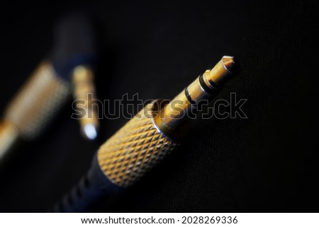 The gold-plated TRS connectors for the analog audio signal are placed against a black background. Mini-jack - 3.5 mm. Audiophile equipment concept. Shallow depth of field. Selective focusing. Macro Royalty-Free Stock Photo #2028269336