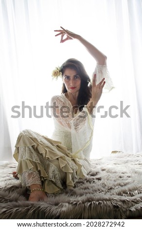 Flamenco dancer dressed in white, backlit photo. Middle-aged dancer woman dark hair