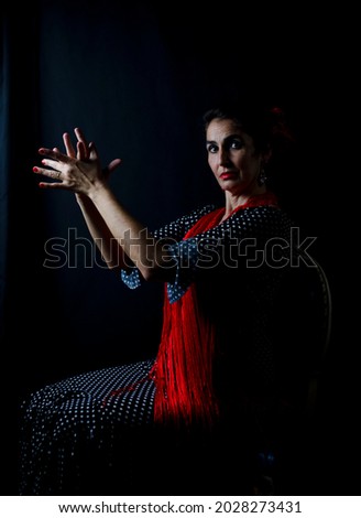 Flamenco dancer dressed in black and red, photo in low key. Middle-aged dancer woman dark hair