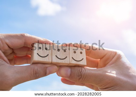 Smile face and cart icon on wood cube. Optimistic person or people feeling inside and service rating when shopping, satisfaction concept in business. Royalty-Free Stock Photo #2028282005