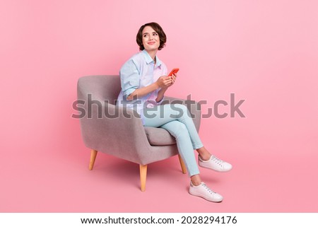 Full length body size photo woman sitting browsing internet on smartphone looking copyspace isolated pastel pink color background Royalty-Free Stock Photo #2028294176