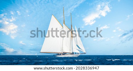 Stunning view of a wooden sailboat with white sails sailing on a blue water during a sunny day. Isola di Spargi, Maddalena Archipelago, Costa Smeralda, Sardinia, Italy. Royalty-Free Stock Photo #2028336947