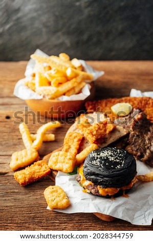 Fast food concept with french fries and burger on wooden background