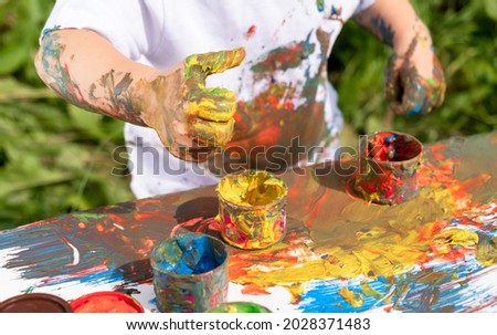 A small child paints with finger paint and all gets dirty in it. Close-up of a hand.