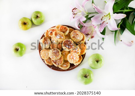 breakfast with cheesecakes sprinkled with powdered sugar and pink lilies on a white table lit by the sun, horizontal,