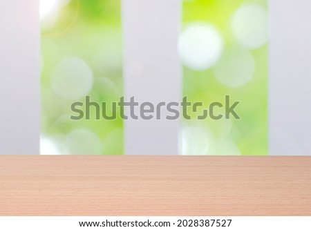 Light brown wooden board with blurred green window background