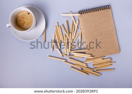 many wooden pencils lie on a beige notebook, next to it is a white mug with coffee. The concept of learning and creativity. High quality photo