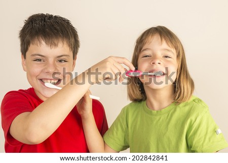 Funny portrait of a young girl and a young boy brushing each other 