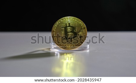 Golden bitcoin on white table on black background.