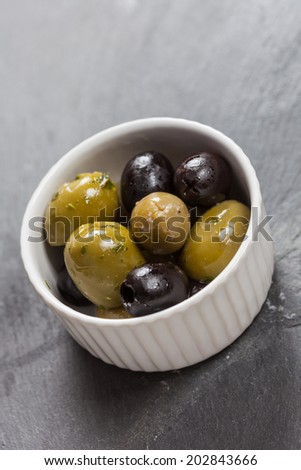 A dish of delicious black and green olives on a slate background