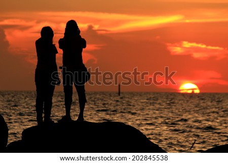 group of people's silhouette on the jetty isolated over sunset and dramatic sky