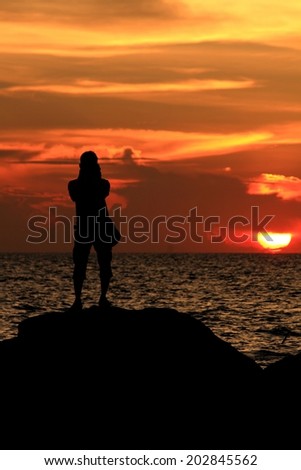 group of people's silhouette on the jetty isolated over sunset and dramatic sky