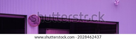 Purple corrugated sheet metal warehouse with open roll up door , convex traffic mirror and lamp