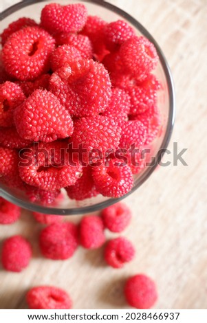 Closeup top view photo of raspberrys in a bowl, on the wooden table