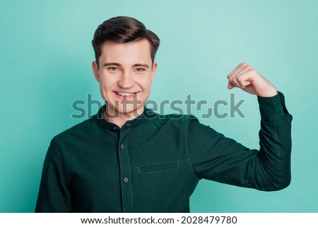 Young business man show arm muscle isolated on turquoise background