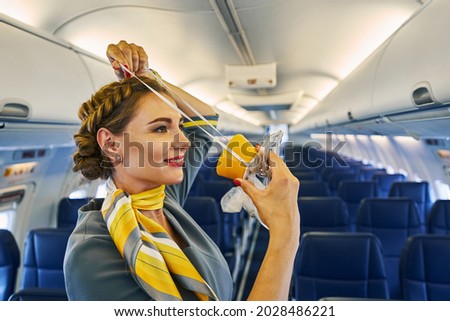 Stewardess using a breathing apparatus during a pre-flight safety demonstration Royalty-Free Stock Photo #2028486221