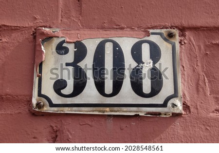 A sign on a wall with the number three hundred eight-308